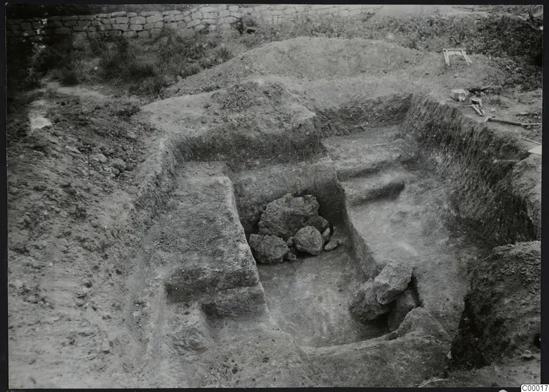 Excavated dromos of Tomb 303 at Vrysi tou Barba, Lapithos, with stone blocks in the cut and tools at the edge