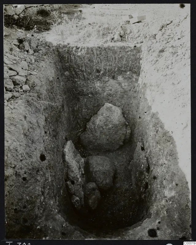 Excavated tomb chamber at Lapithos, Vrysi tou Barba, with large stones lying inside the cut.
