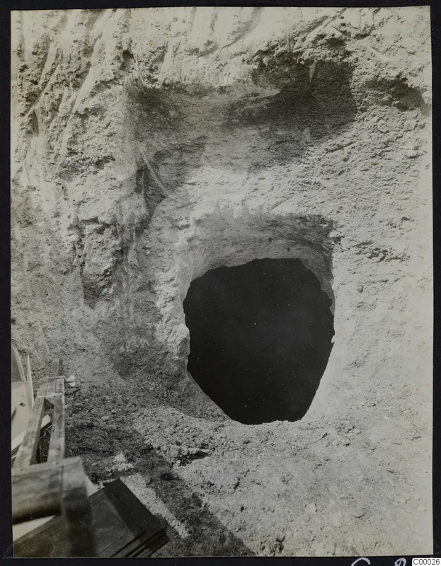 Tomb 302 at Lapithos, Vrysi tou Barba, during excavation, showing a dark tomb opening cut into a pale earth face.