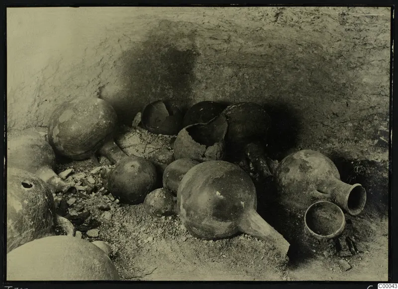 Pottery vessels in situ on the floor of Lapithos Tomb 303A, against a rough tomb wall