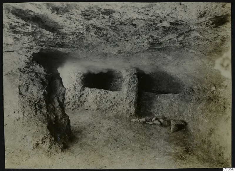 Tomb 313 A at Lapithos, Vrysi tou Barba: rock-cut tomb chamber with standing rock pillars and loose stones on the floor.