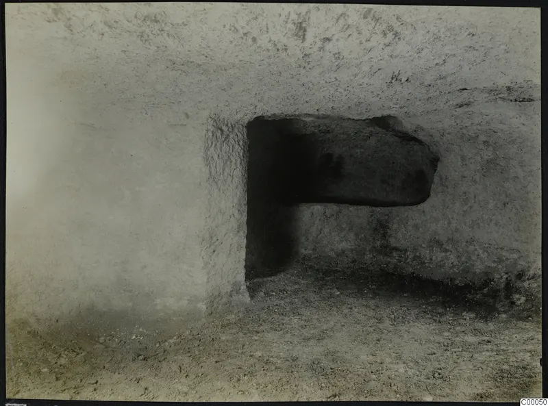 Tomb chamber at Vrysi tou Barba, Lapithos, with a large stone lying in a rectangular opening in the rock wall