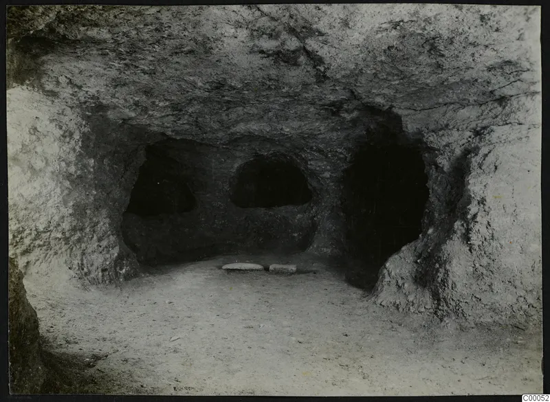 Interior of rock-cut Tomb 313 A at Lapithos, Vrysi tou Barba, with three recesses in the back wall and two flat stones on the floor