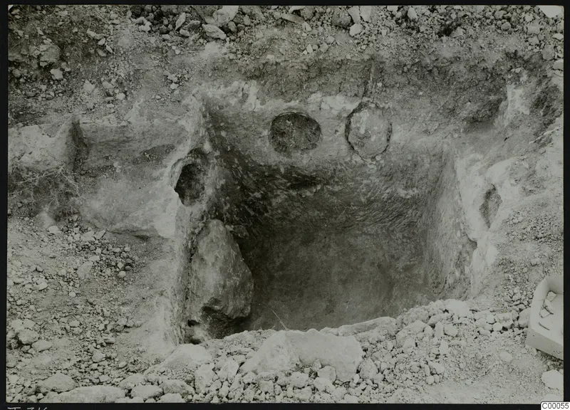 Rock-cut tomb chamber 316 at Vrysi tou Barba, Lapithos, during excavation, with stones and a box