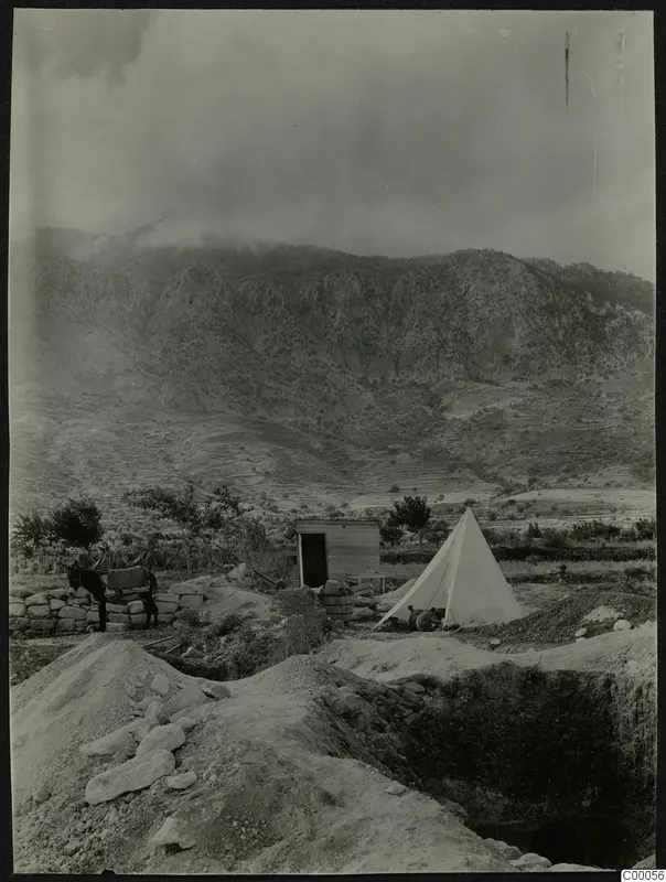 Excavation at Lapithos with a white tent, a small wooden hut and a donkey beside a stone wall, with mountains behind.