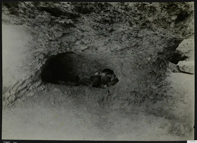 Rock-cut tomb chamber opening at Lapithos, Vrysi tou Barba, with stones and objects during excavation