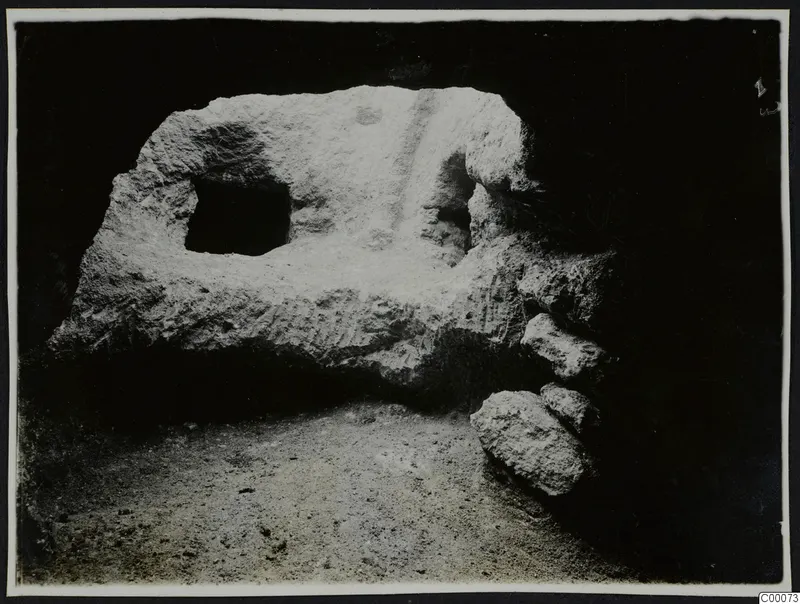 Tomb 306 at Lapithos during excavation, showing the tomb chamber wall with a square opening and stones at the right.
