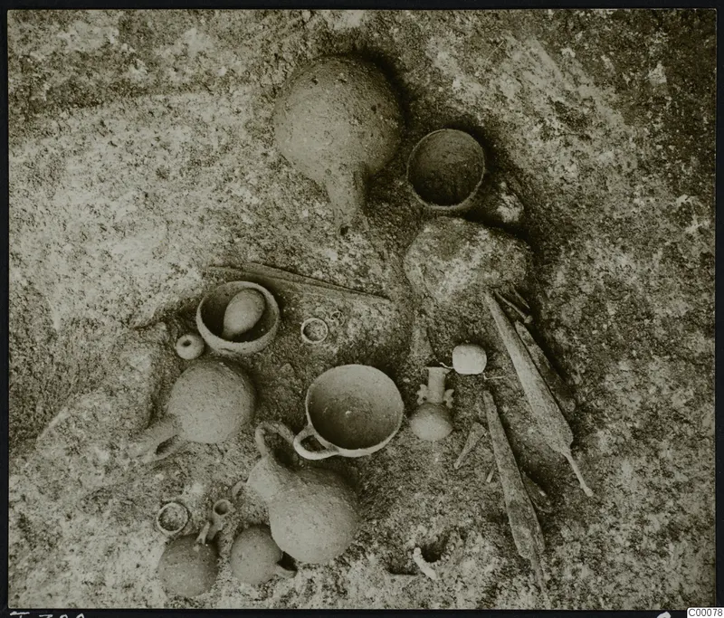 Tomb 320 at Lapithos: pottery vessels and small objects lying on the tomb chamber floor during excavation.