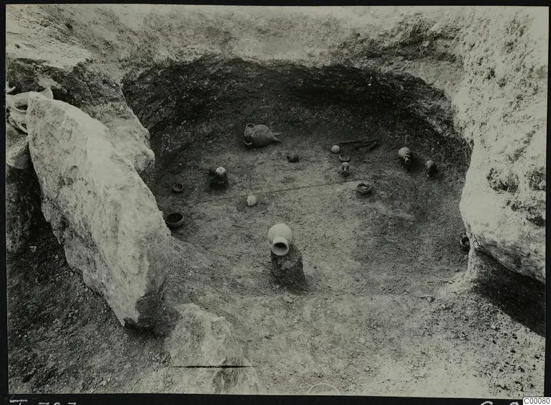Tomb 323 at Lapithos, Vrysi tou Barba, during excavation, with pottery vessels scattered on the chamber floor.