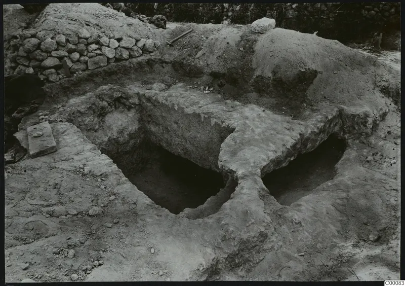 Tomb 405 at Lapithos Kastros during excavation, showing two rectangular openings cut into the ground with spoil heaps around them