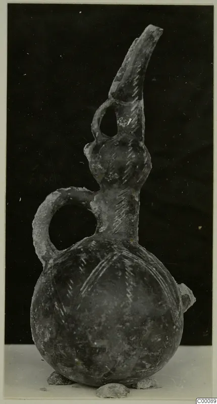 Pottery jug with a tall spout-like neck, two handles and pale hatched lines on its body, photographed against a dark background