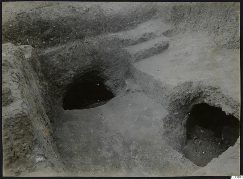 Two excavated tomb openings in an earth cutting at Vrysi tou Barba, Lapithos, with a stepped cut above them