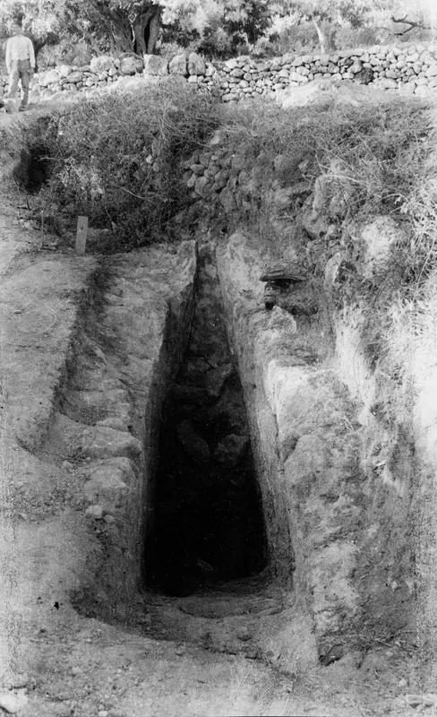 Dromos leading down to the dark entrance of Tomb 406 at Lapithos, with a dry stone wall behind
