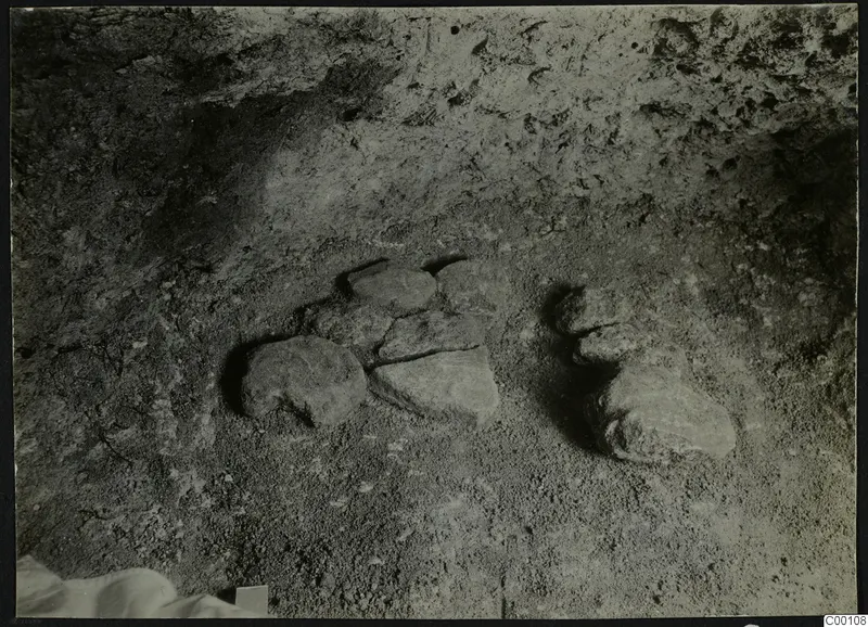 Tomb 301 at Lapithos during excavation, showing stones lying on the sandy floor of the tomb chamber.