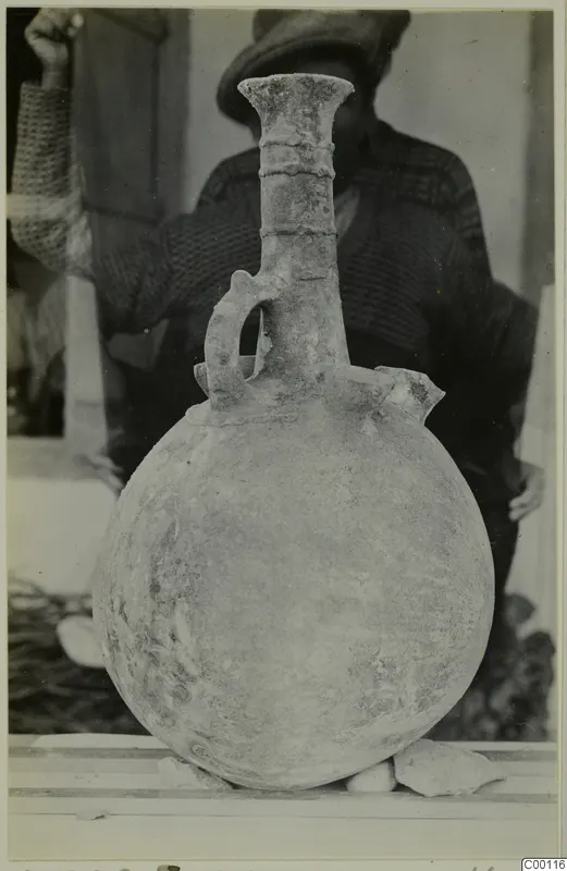 Red Polished II jug with a long neck, ring bands and one strap handle, in front of a man in a cap