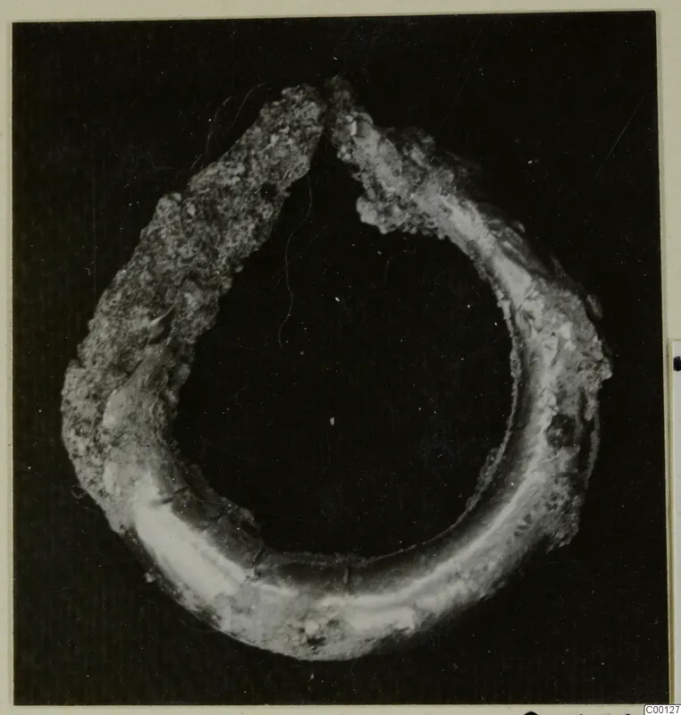 Bronze earring, an open hoop with a corroded, crusted surface, photographed against a dark background.
