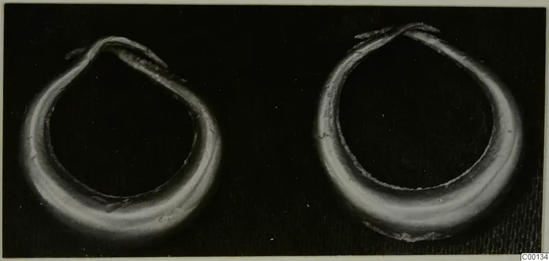 Two gold rings from Lapithos with overlapping open ends, photographed on a dark background