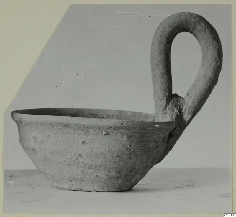 Pottery bowl with a large loop handle on one side, photographed against a plain background.