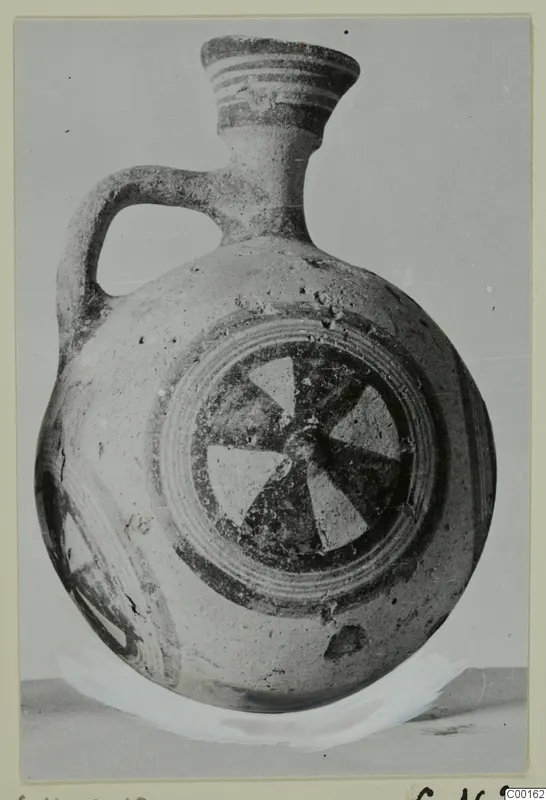 White Painted I jug with a strap handle, banded neck and a pinwheel motif on the body
