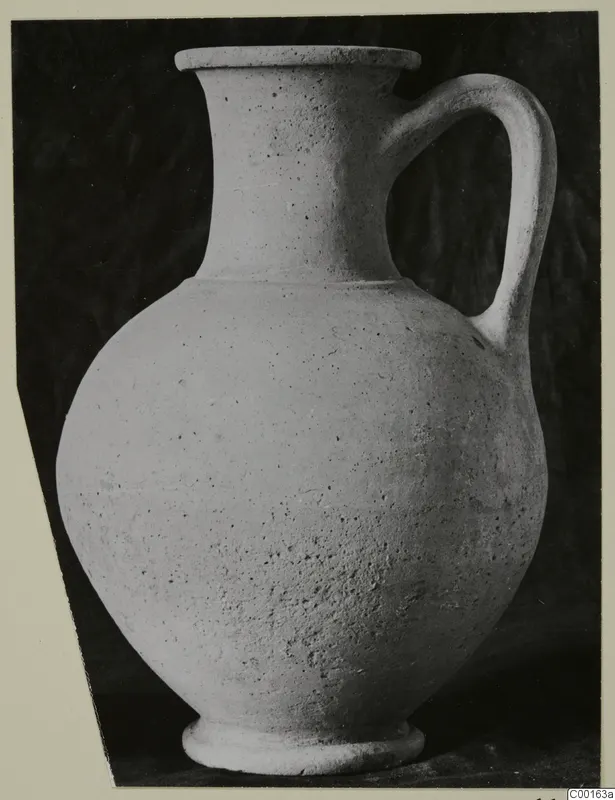 Plain pottery jug with a single loop handle, shown against a dark backdrop.