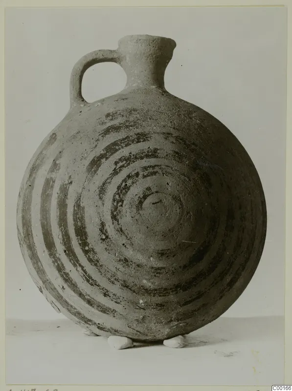 White Painted I jug with a strap handle and dark concentric circles painted on its round body