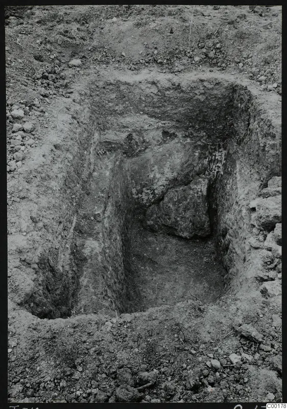 Excavated tomb chamber at Vrysi tou Barba, Lapithos, with a large stone block against the back wall during excavation.