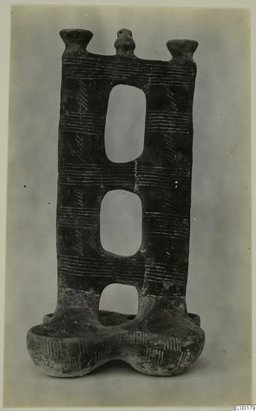 Dark pottery vessel with three oval openings, two cup-like rims at the top and a two-lobed base, from Lapithos