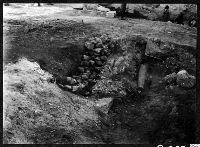 Excavation trench at the theatre at Soli, with a stone wall on the left and a cylindrical stone piece in the cut.