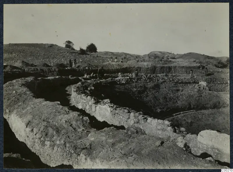 Excavation of the theatre at Soli, with exposed stone walls and figures working in the trenches.