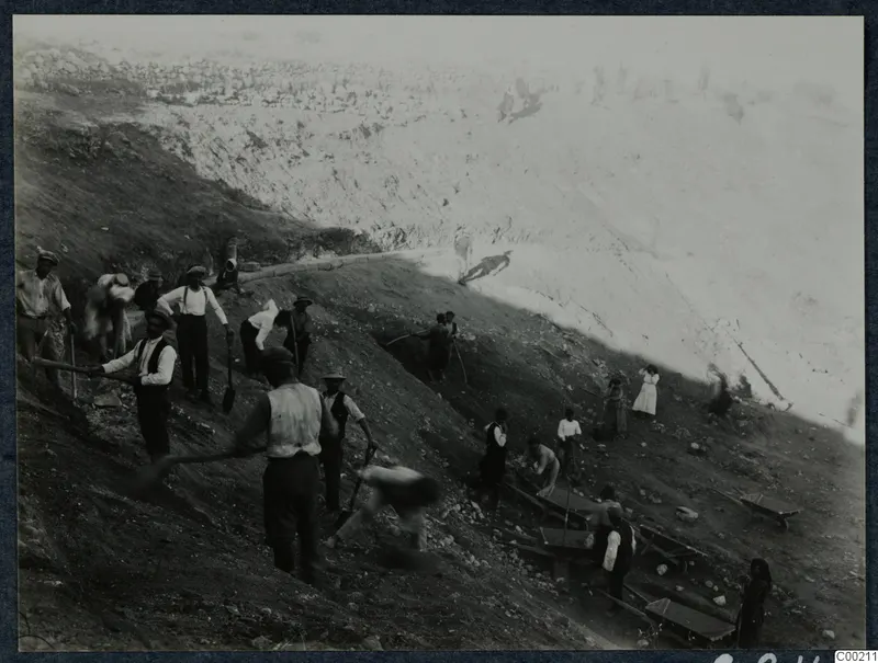 Excavation at the theatre at Soli, with workers digging a steep slope and carrying stones away in wheelbarrows.