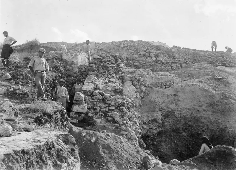 Excavation of rubble substructure walls at Soli, with workers standing and digging among the exposed stones