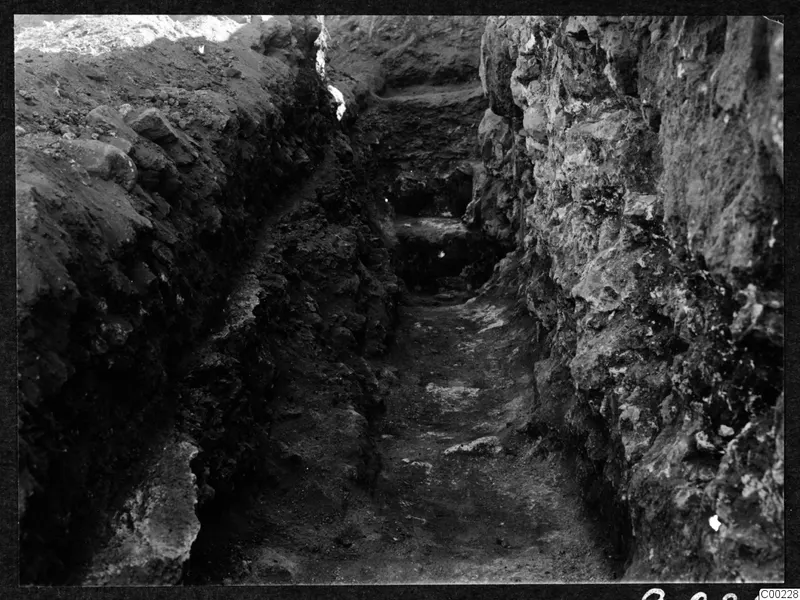Excavation trench at Soli with exposed stone walling on the right and layered soil on the left.