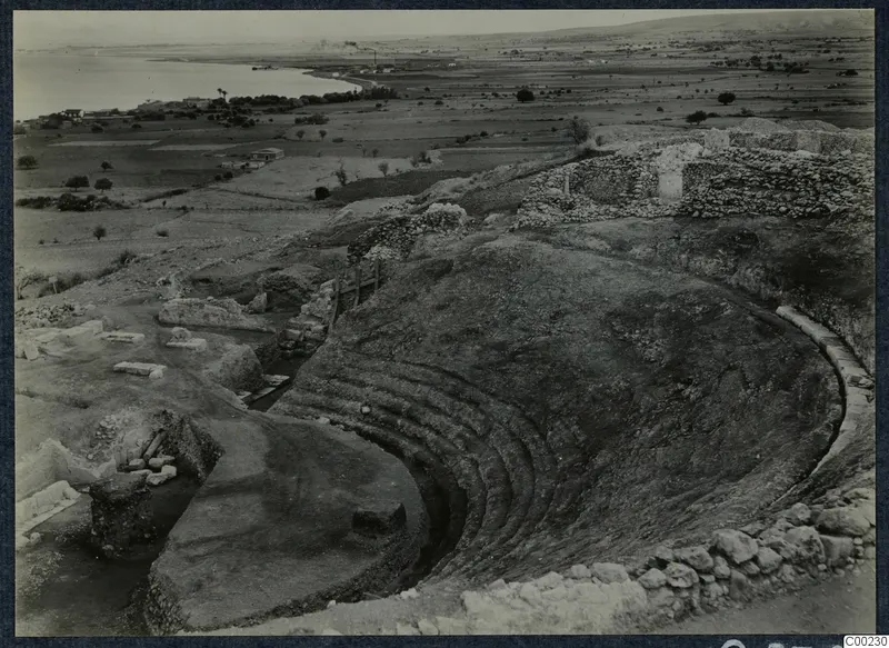 Excavated theatre at Soli with curved tiers of seating cut into the slope, with the sea and plain beyond.