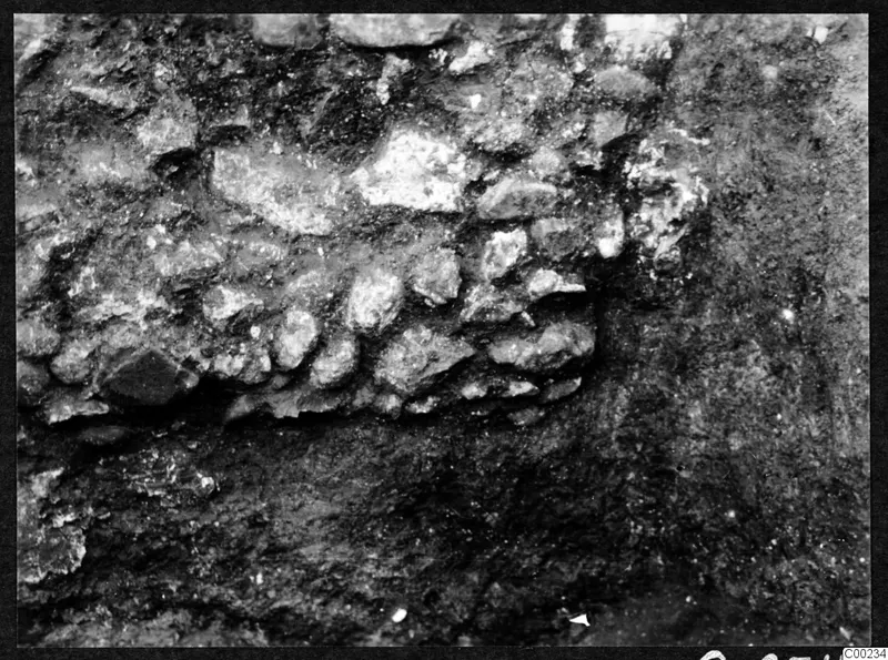 Close view of irregular stones packed together in dark excavated soil at Soli theatre