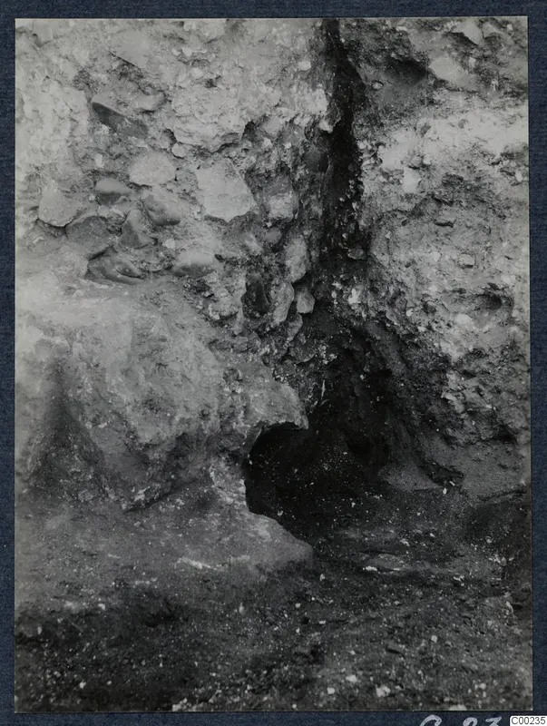Excavated earth face at Soli with embedded stones and a dark hollow at its base