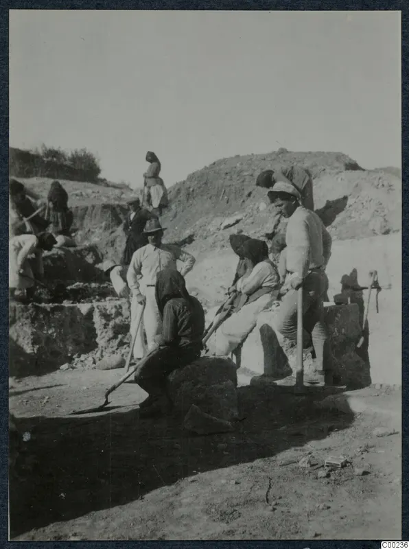 Workers with spades and picks among large stone blocks at the excavation of the theatre at Soli