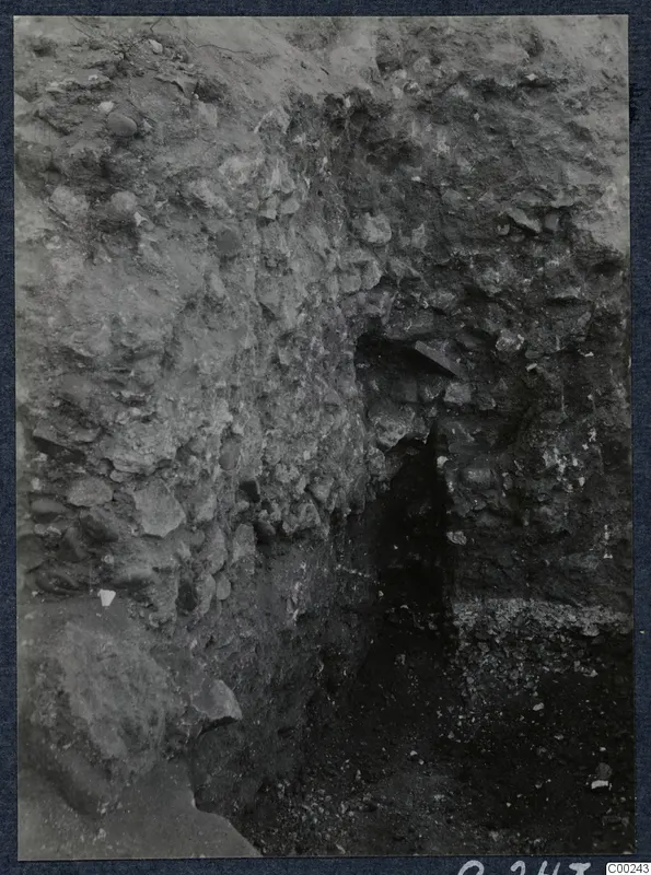 Excavated rubble-stone wall at the theatre at Soli, with a narrow dark opening at centre right.