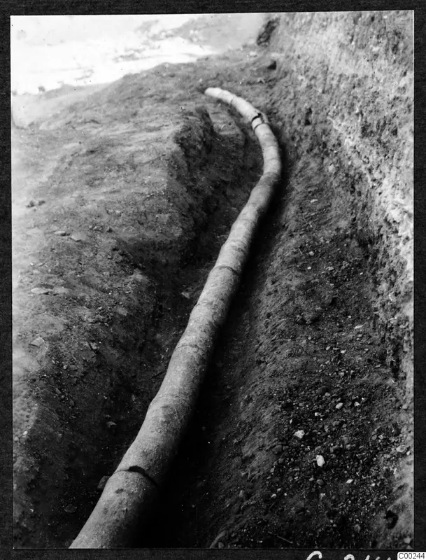 Long curved pipe lying in an excavated trench at Soli