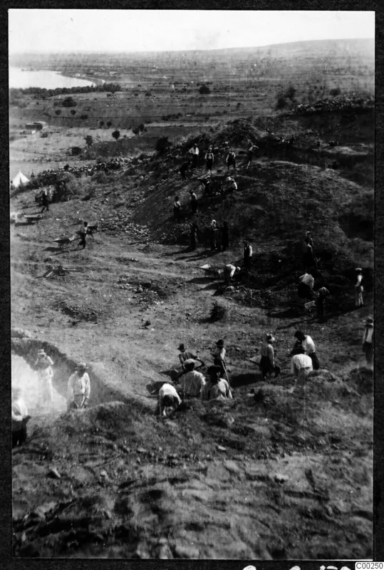 Excavation at Soli, the theatre: workers digging on a hillside above a flat plain and a stretch of water.
