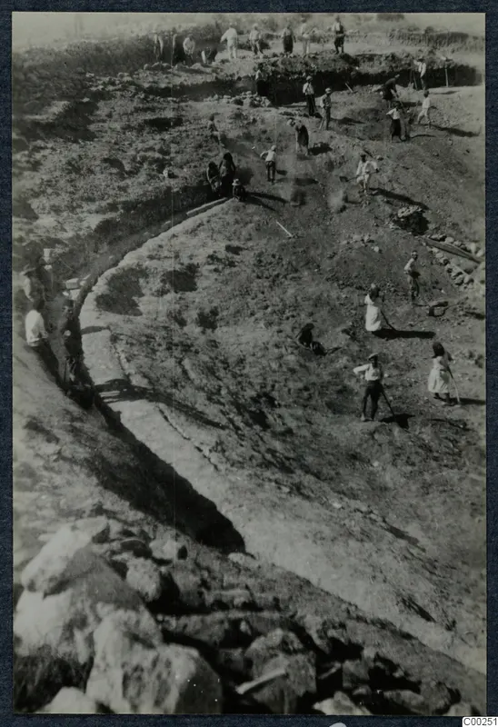 Excavation at the theatre at Soli, with workers digging a curved trench beside exposed stonework.