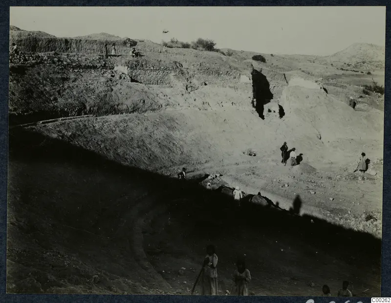 Excavation at the theatre at Soli, with stone walls along the cutting and people working among the earth and stones.