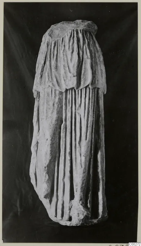 Half of a draped marble sculpture, photographed against a dark background.