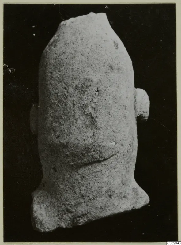 Terracotta fragment of a figure with a broken top and two side projections, photographed alone on a dark background