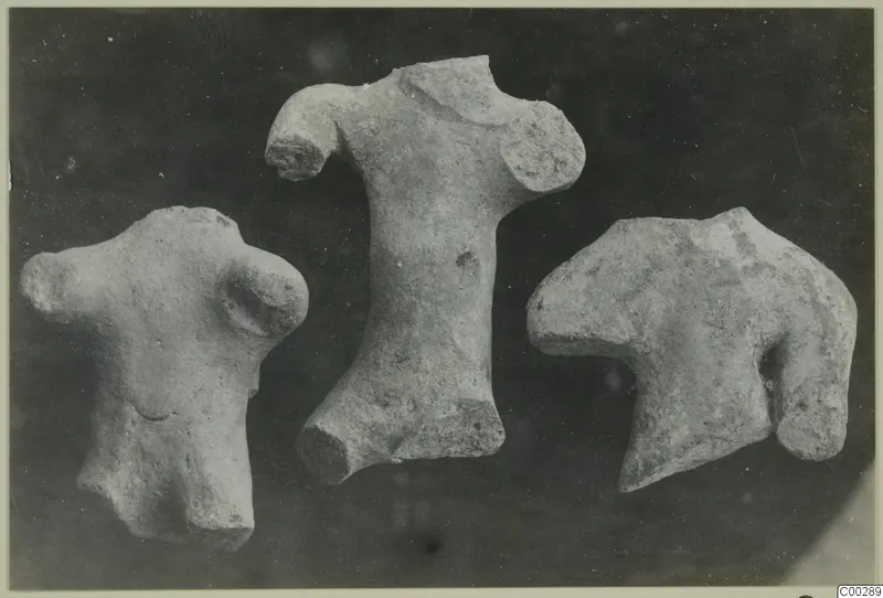 Three terracotta figurine fragments, torsos without heads or limbs, set against a dark background.