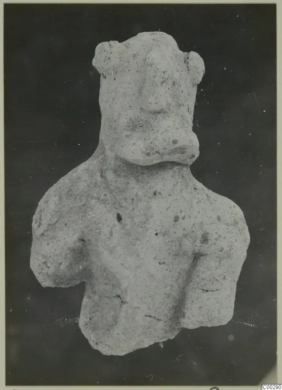 Terracotta figurine of a head and upper body with a broad nose and knob-like ears, photographed against a dark background