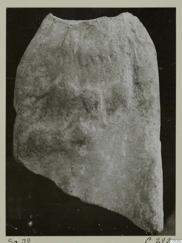 Fragment of a terracotta minor plastic object against a dark background
