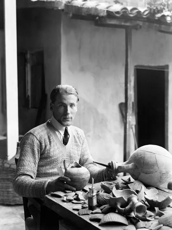 Alfred Westholm conserving pots at a table covered with sherds, in a courtyard in Nicosia