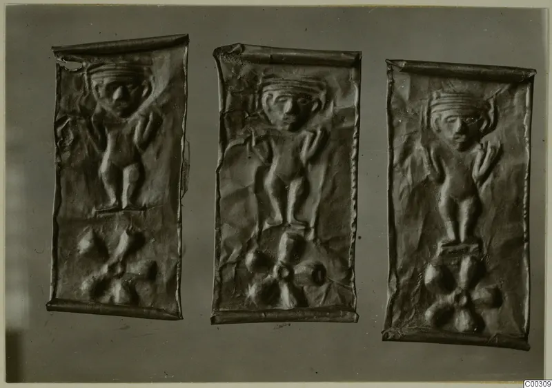 Three embossed thin metal plaques, each with a relief figure with raised arms above a rosette motif.