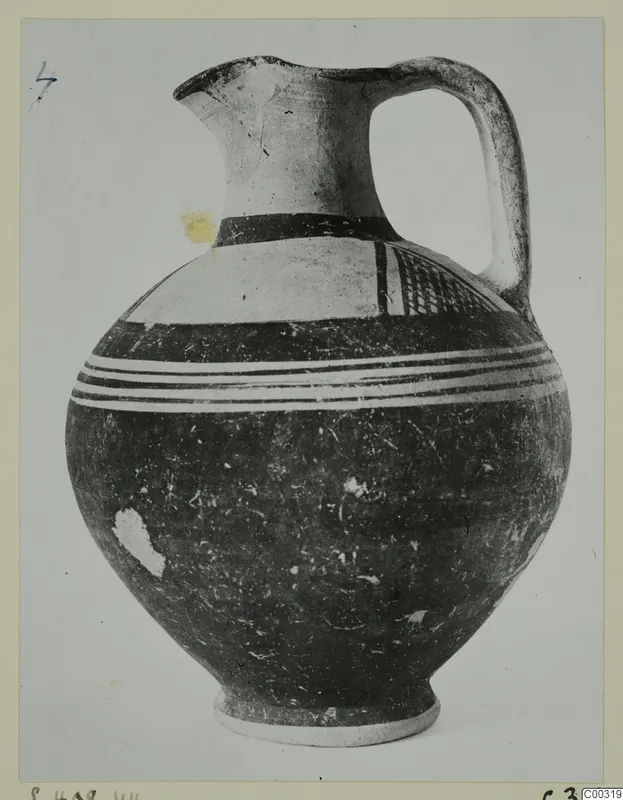 Pottery White Painted I jug with a high handle, dark bands and white painted zones on a rounded body.