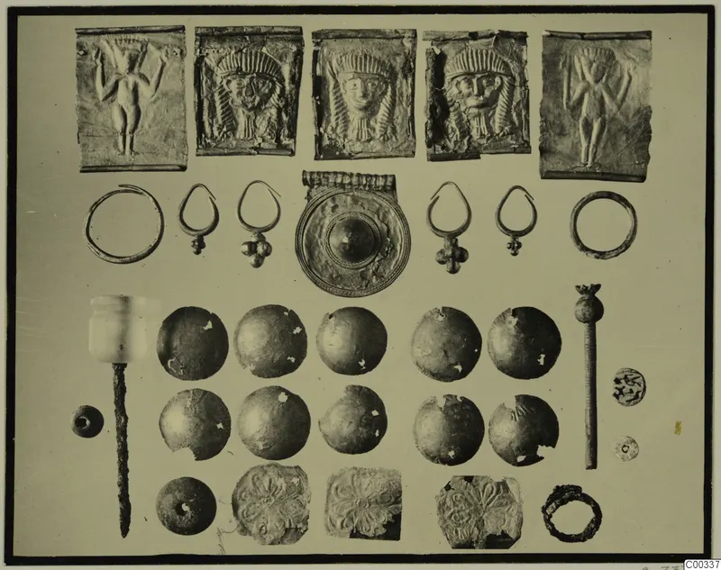 Metal jewellery, embossed plaques and a pale stone object from Lapithos Tomb 403, laid out in rows for photographing